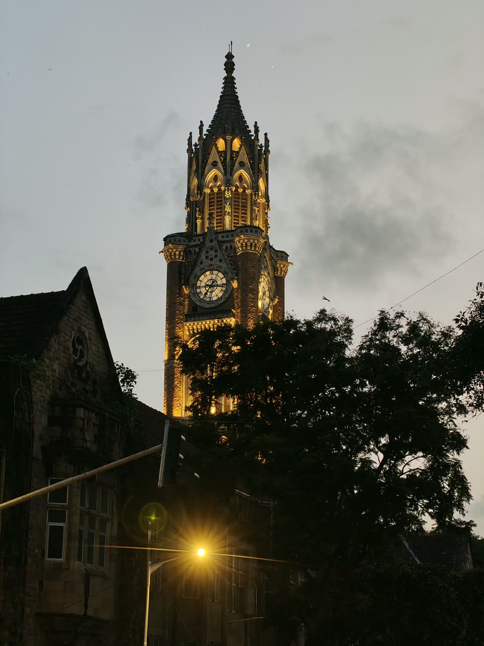 The Rajabai clock tower lit gold at dusk